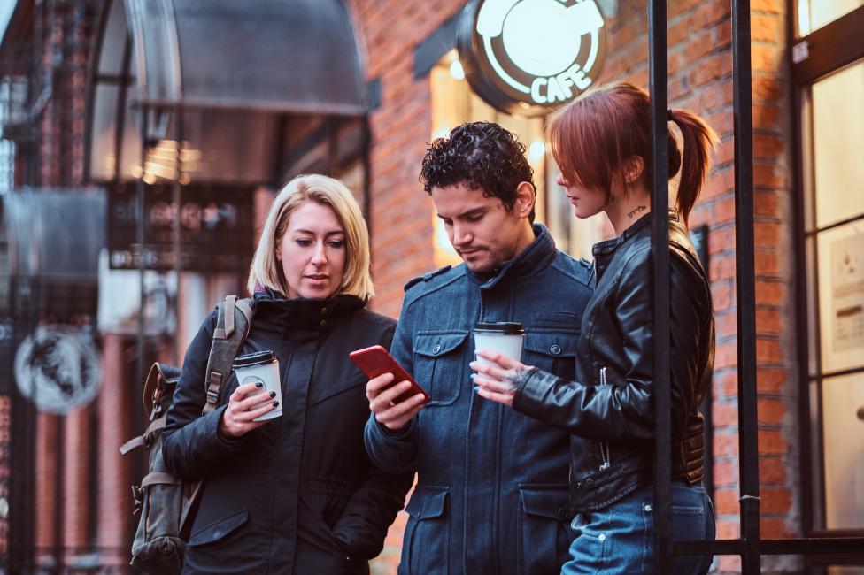 Social Media Advertising: Drei Freunde schauen gemeinsam ins Handy